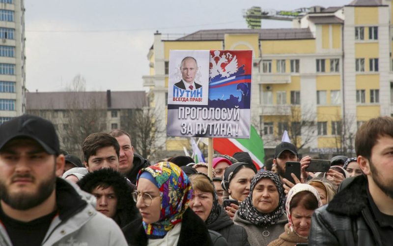 People take part in an election event in the Chechen capital Grozny, Russia. The slogan next to Putin on the poster reads: "Putin is always right! Vote for Putin!" PHOTO/Chingis Kondarov/Reuters
