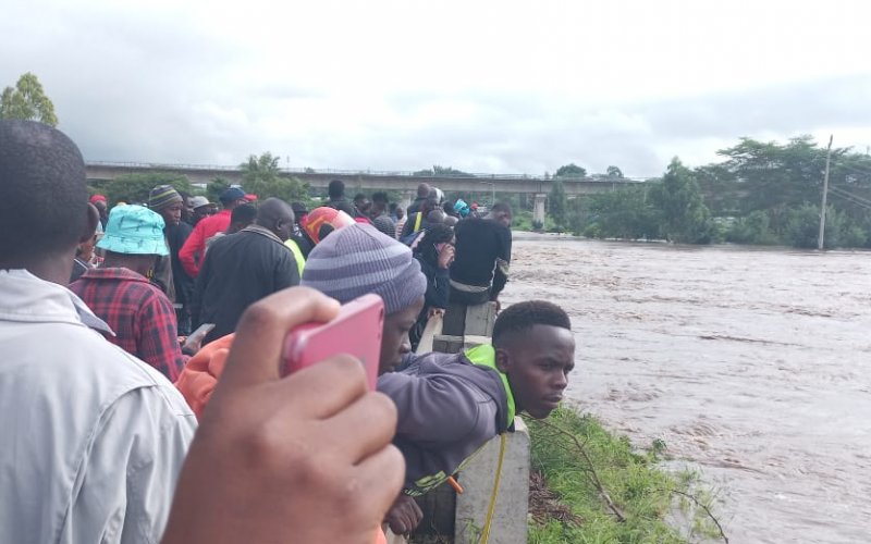 Onlookers at River Athi-river after it burst its banks this morning after heavy downpour in the upper regions of Kitengela reserve and Sholinke. PHOTO/Christine Musa